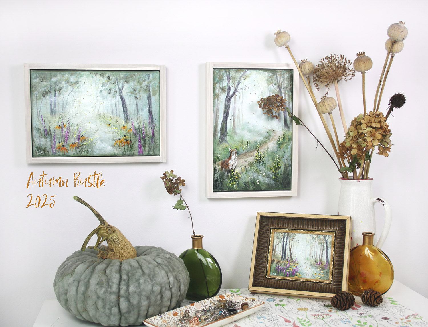 Autumn-themed decor with framed artworks original paintings, a pumpkin, and decorative items on a table.
