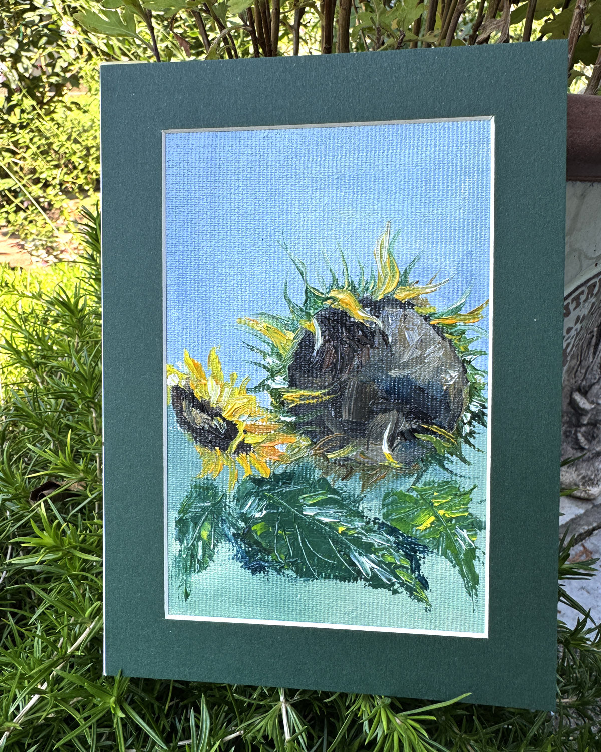Miniature oil painting of sunflowers on a blue background, framed in green.