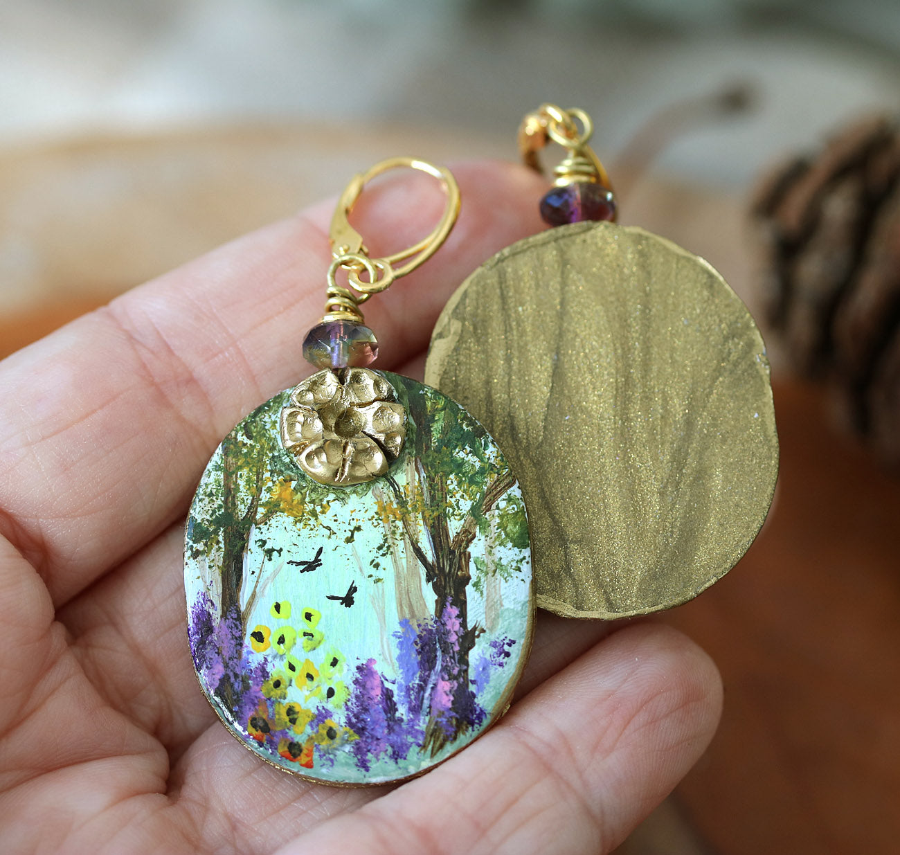 Hand painted art earrings by Katie Koroleva with wildflowers and forest landscape