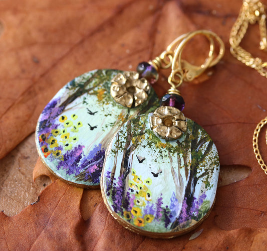 Hand painted art earrings by Katie Koroleva with wildflowers and forest landscape