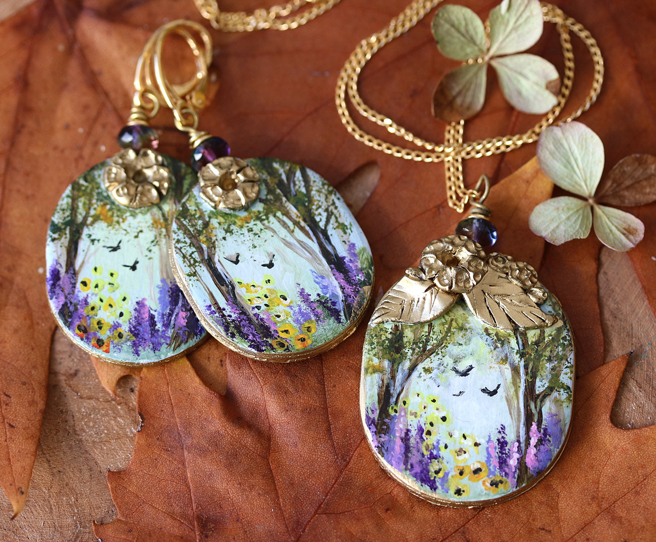 Hand painted art jewelry set by Katie Koroleva with wildflowers and forest landscape
