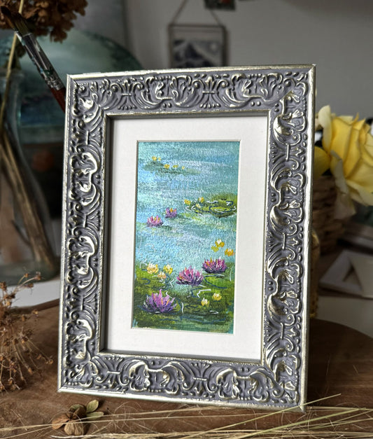 Framed artwork of a lily pond scene with decorative silver frame.
