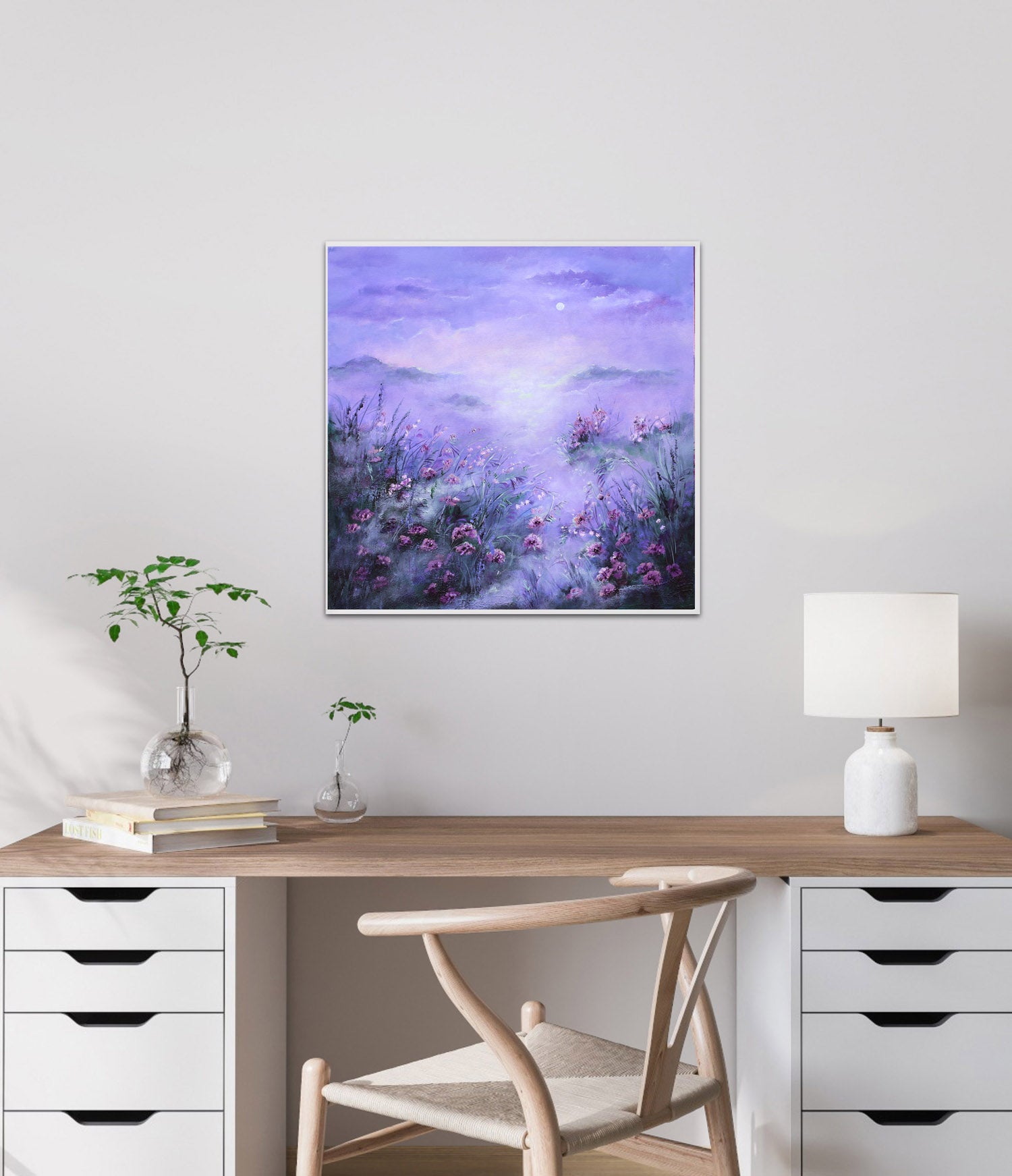 Framed artwork of a purple landscape with flowers on a wall above a desk.