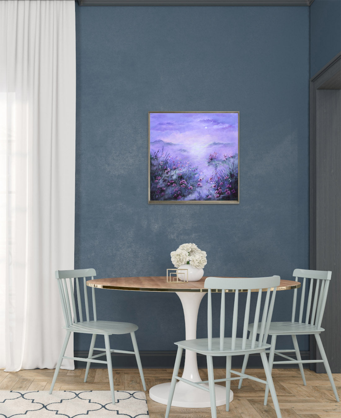 Dining room with a table and chairs against a blue wall with a framed painting.