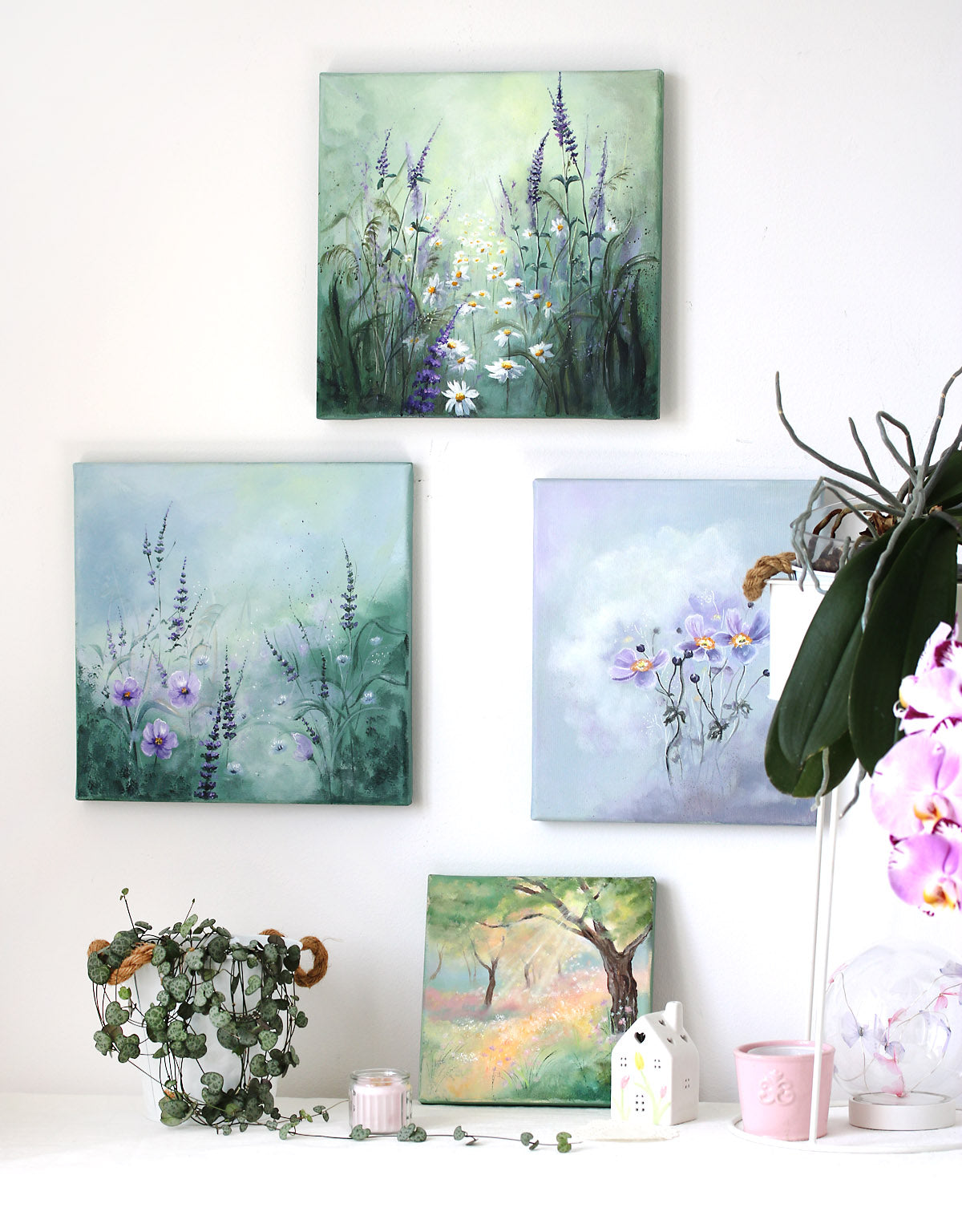 Set of four nature-themed paintings on a wall with decorative plants.