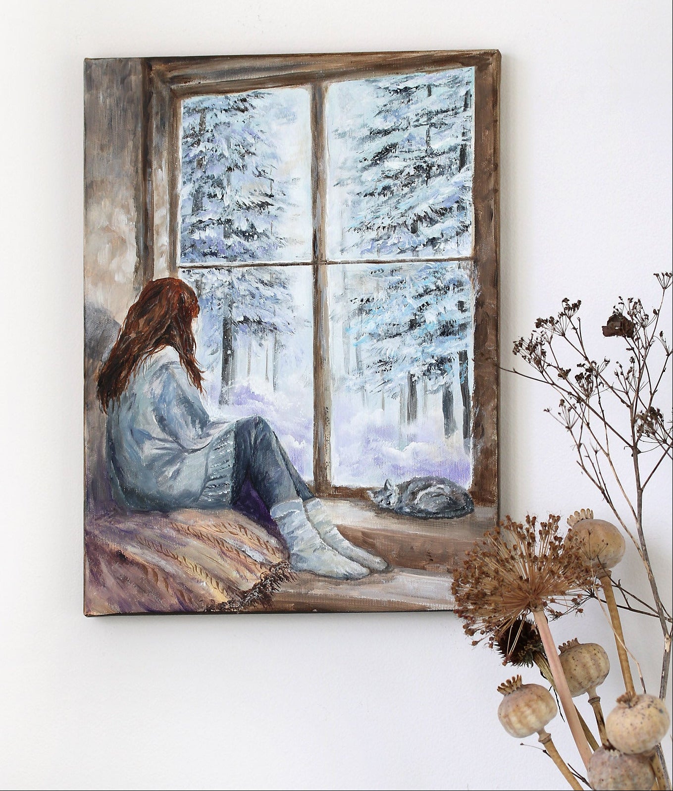 Painting of a woman sitting by a window with a snowy landscape, placed on a white wall.