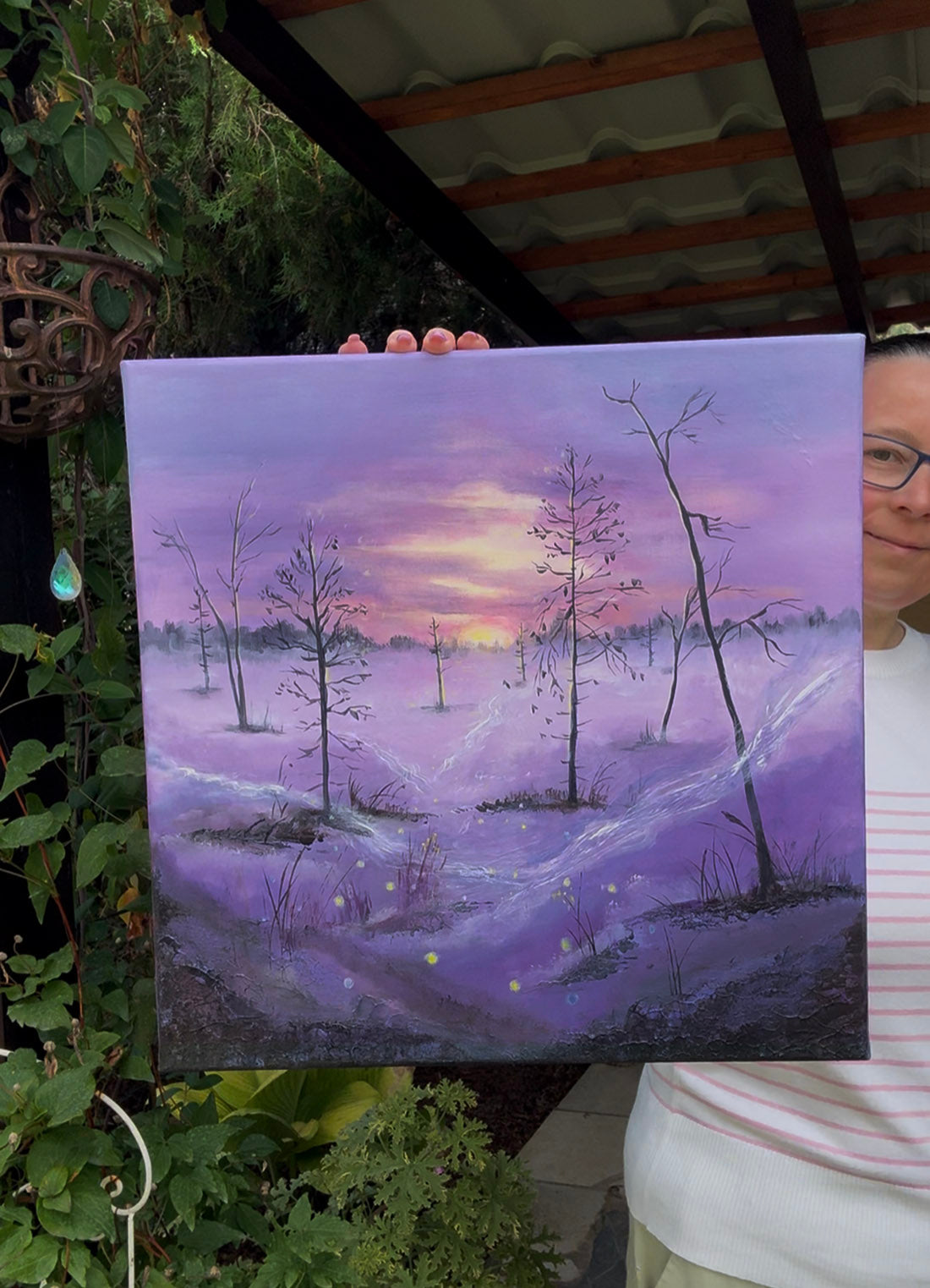 A square painting of a misty enchanted forest landscape in shades of purple, lavender, and pink, with bare trees, a glowing yellow-orange sun on the horizon, and glowing yellow firefly-like lights scattered across the scene.