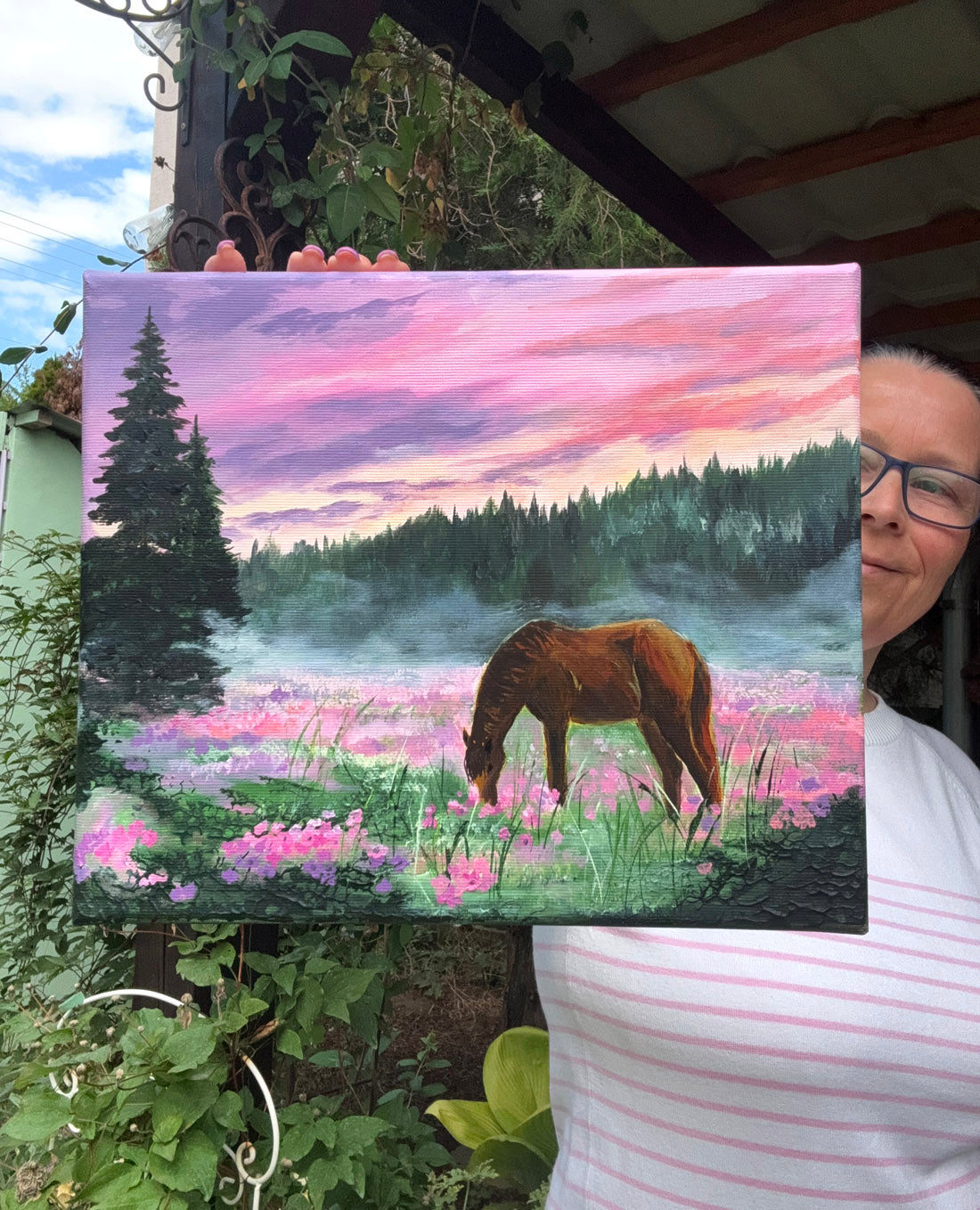 A painted landscape scene showing a brown horse grazing in a field of pink and purple flowers, with misty trees and a pink-purple sky in the background.
