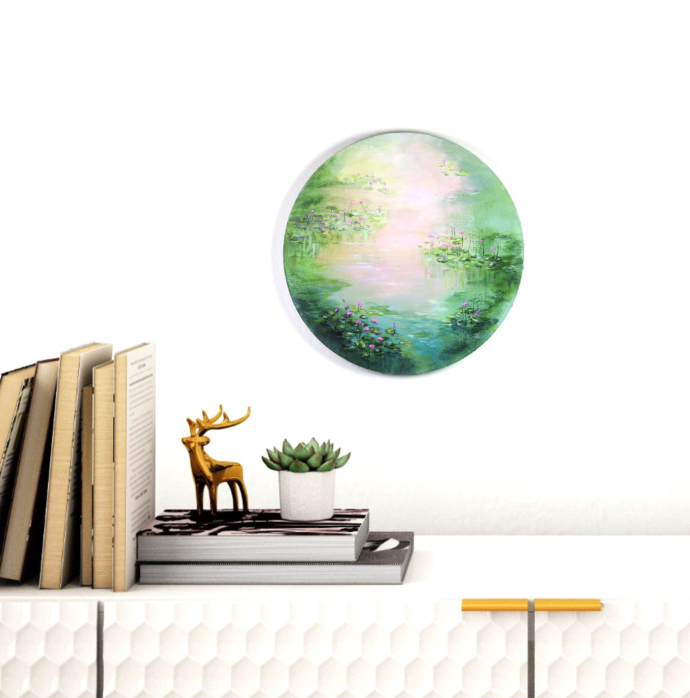 Decorative wall art of a green landscape with books and a small statue on a white surface.