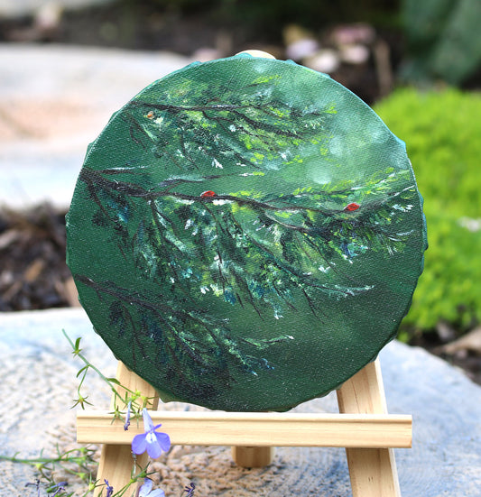 Round green pine tree branch oil painting on a small easel 