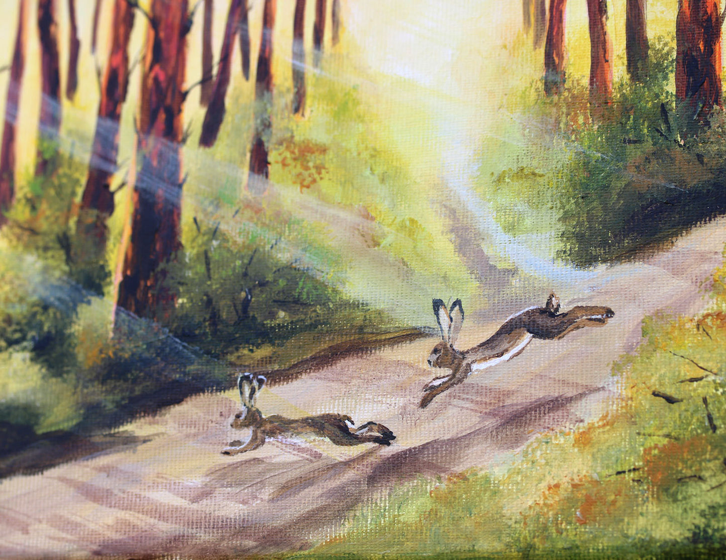 A painted forest scene showing two rabbits running along a sunlit path between tall trees, with light rays streaming through the woods.