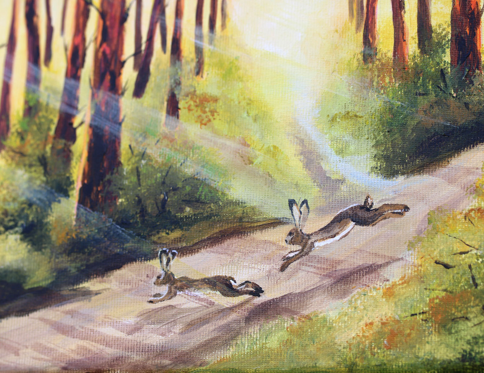A painted forest scene showing two rabbits running along a sunlit path between tall trees, with light rays streaming through the woods.