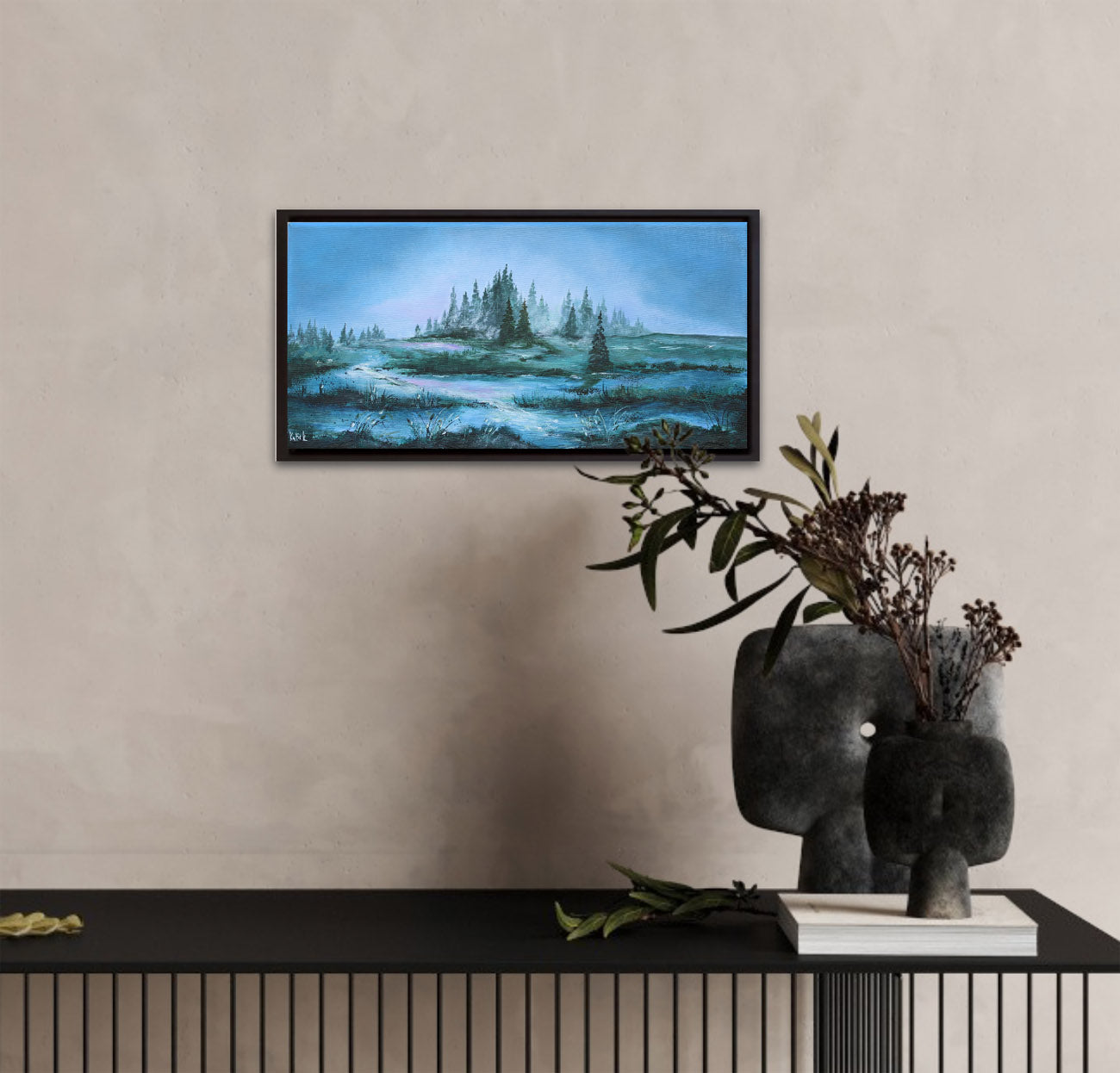 Framed landscape painting on a wall above a black console table with decorative items.