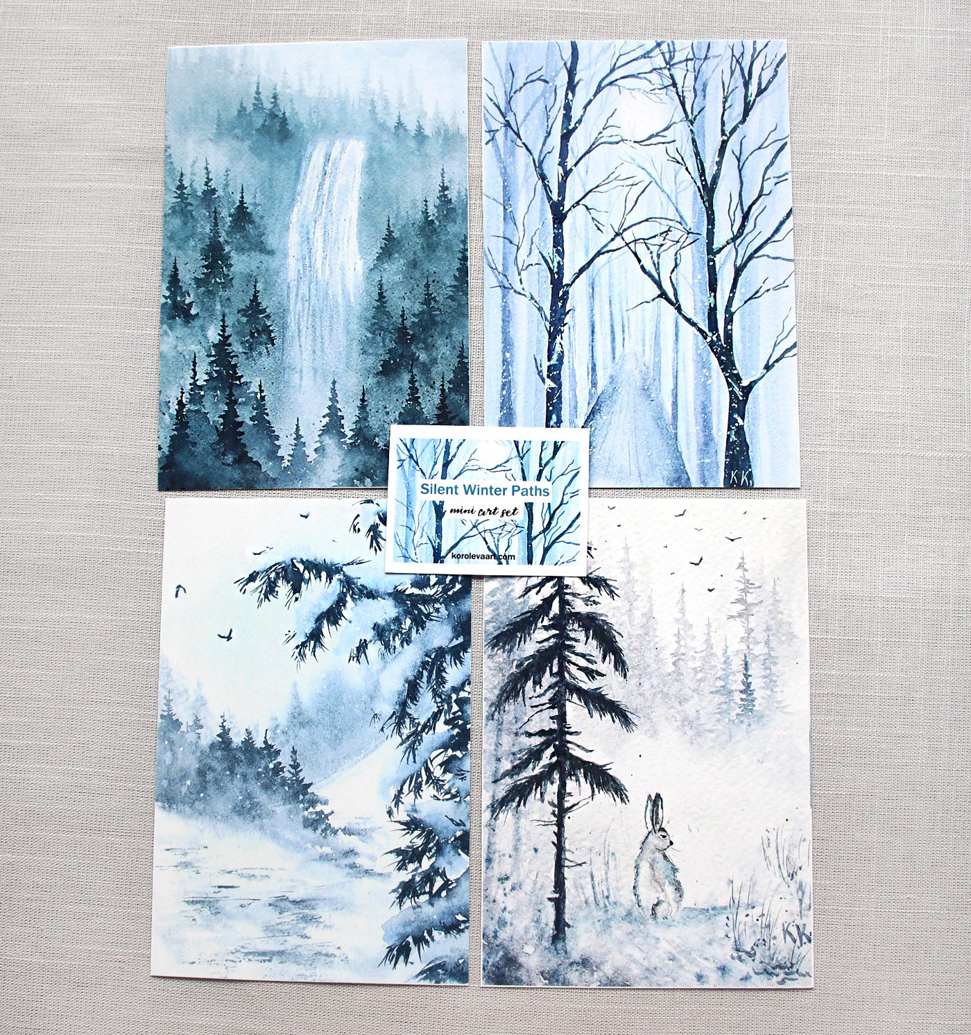 Set of four winter-themed watercolor prints featuring a forest, trees, a rabbit, and a waterfall.